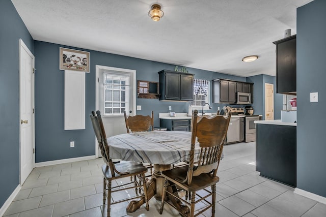 dining space featuring a healthy amount of sunlight, a textured ceiling, baseboards, and light tile patterned floors