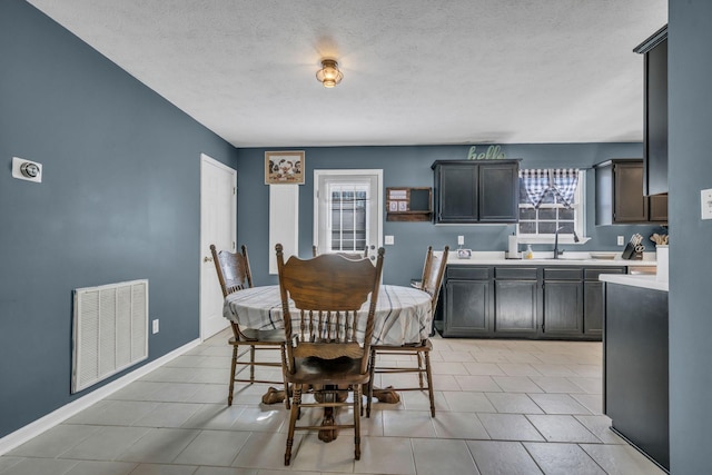 dining space featuring light tile patterned floors, baseboards, visible vents, and a textured ceiling