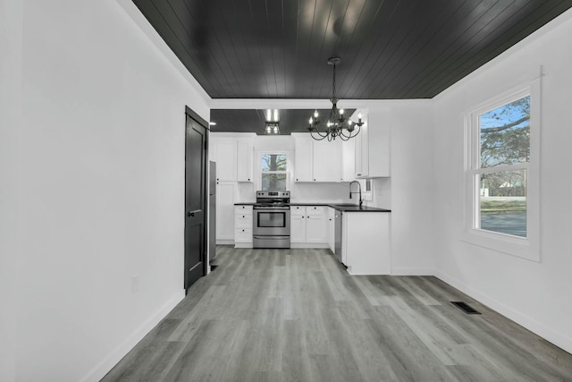 kitchen featuring baseboards, a chandelier, stainless steel appliances, white cabinetry, and a sink