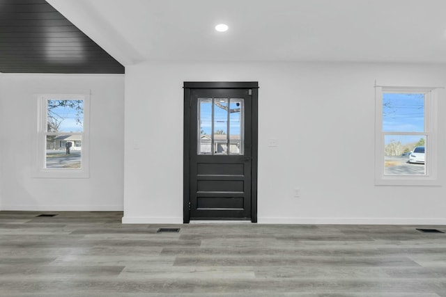 foyer featuring a healthy amount of sunlight, baseboards, visible vents, and wood finished floors