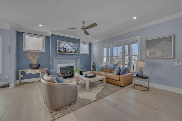 living room featuring a glass covered fireplace, crown molding, baseboards, and wood finished floors