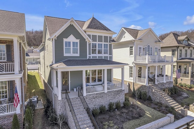 view of front of home with covered porch, a residential view, stairway, and roof with shingles