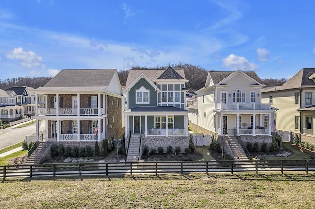 view of front of house featuring a porch, a fenced front yard, a balcony, stairs, and a residential view