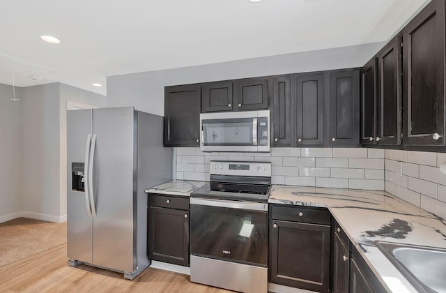 kitchen with light stone counters, tasteful backsplash, recessed lighting, appliances with stainless steel finishes, and light wood-style floors