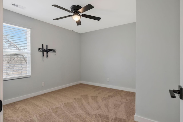 carpeted empty room with visible vents, baseboards, and ceiling fan