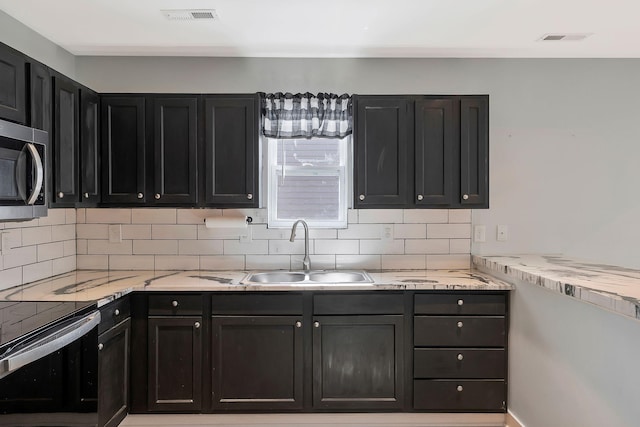 kitchen with visible vents, dark cabinetry, stainless steel microwave, and a sink