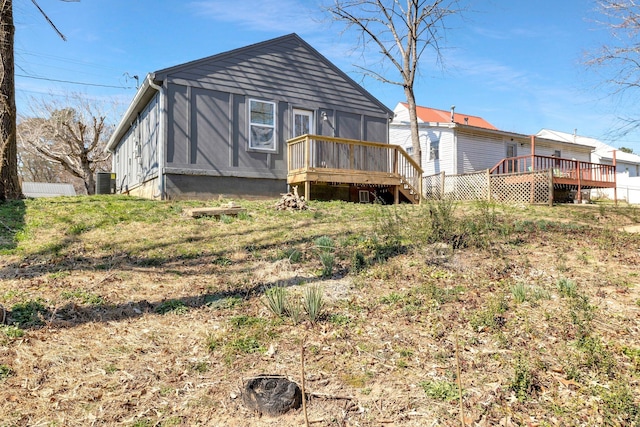 rear view of house with central AC unit, a wooden deck, and a sunroom