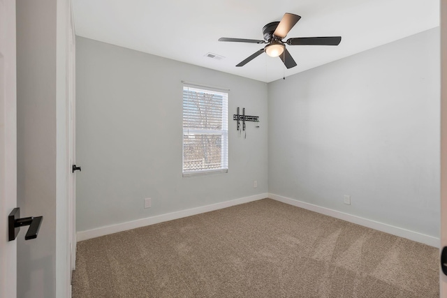 empty room with carpet floors, a ceiling fan, visible vents, and baseboards