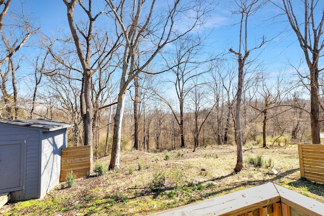 view of yard with an outbuilding, a forest view, and a storage unit