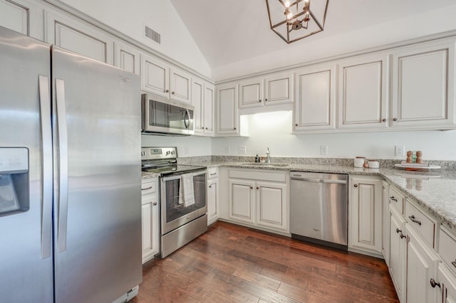 kitchen featuring stainless steel appliances, a sink, visible vents, vaulted ceiling, and dark wood-style floors