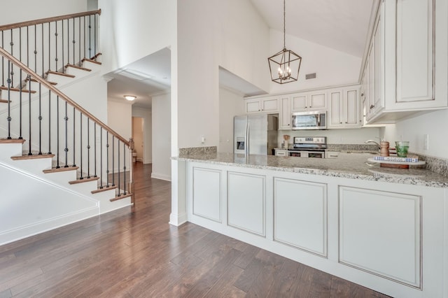 kitchen with light stone counters, high vaulted ceiling, stainless steel appliances, and dark wood finished floors