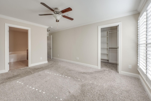 unfurnished bedroom with baseboards, a spacious closet, carpet, and crown molding