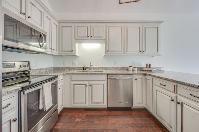 kitchen featuring appliances with stainless steel finishes, dark wood finished floors, a sink, and light stone counters