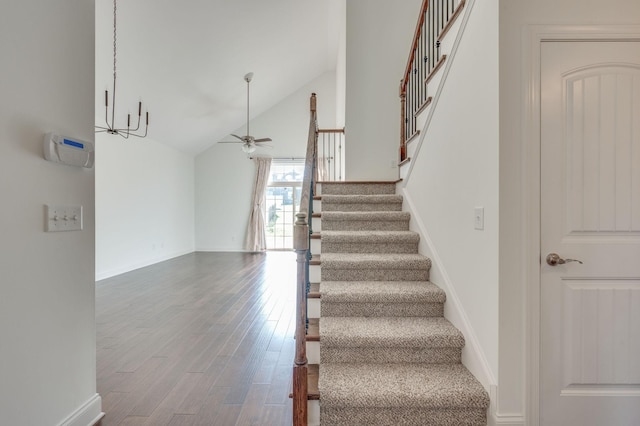 staircase featuring high vaulted ceiling, wood finished floors, a ceiling fan, and baseboards