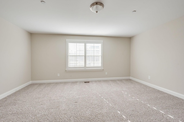 carpeted spare room featuring visible vents and baseboards