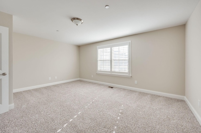 carpeted spare room featuring visible vents and baseboards