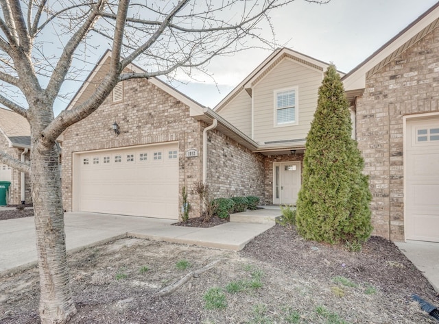 view of front of house featuring a garage, concrete driveway, and brick siding