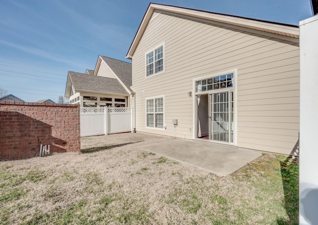 rear view of property with a yard, a patio area, and fence