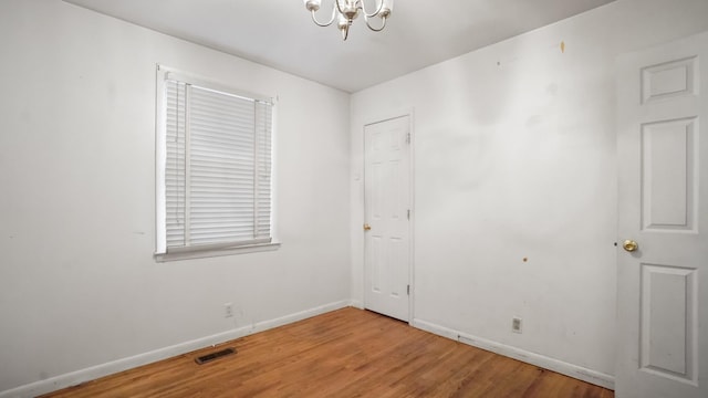 unfurnished room featuring a chandelier, visible vents, light wood finished floors, and baseboards