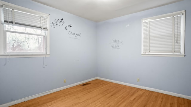 unfurnished room with wood finished floors, visible vents, and baseboards