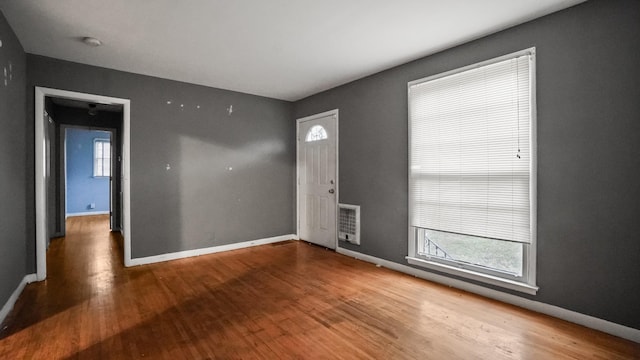 empty room featuring wood finished floors, visible vents, and baseboards