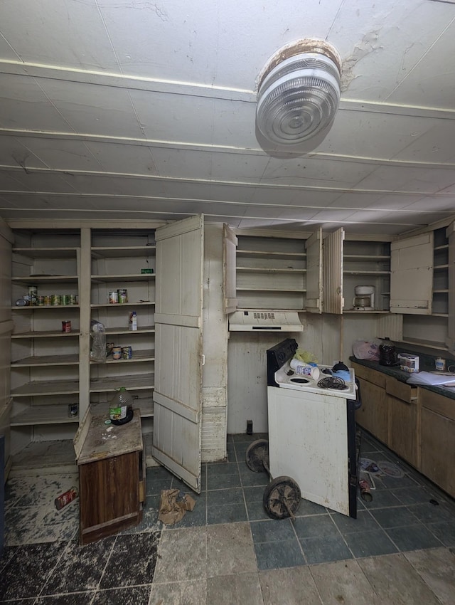 kitchen with stone finish floor, under cabinet range hood, and open shelves