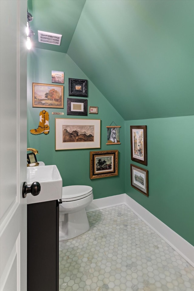 half bathroom with toilet, vaulted ceiling, visible vents, and baseboards