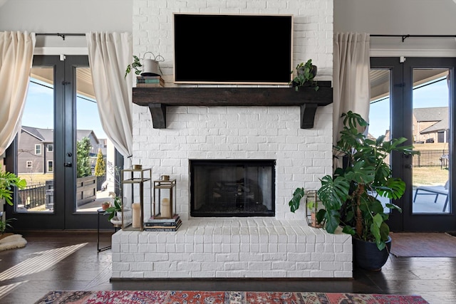 living room with a brick fireplace, french doors, and hardwood / wood-style flooring