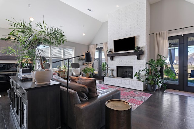 living area featuring visible vents, dark wood finished floors, french doors, a brick fireplace, and high vaulted ceiling