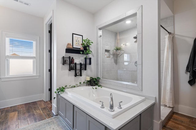 bathroom with a garden tub, a tile shower, and wood finished floors