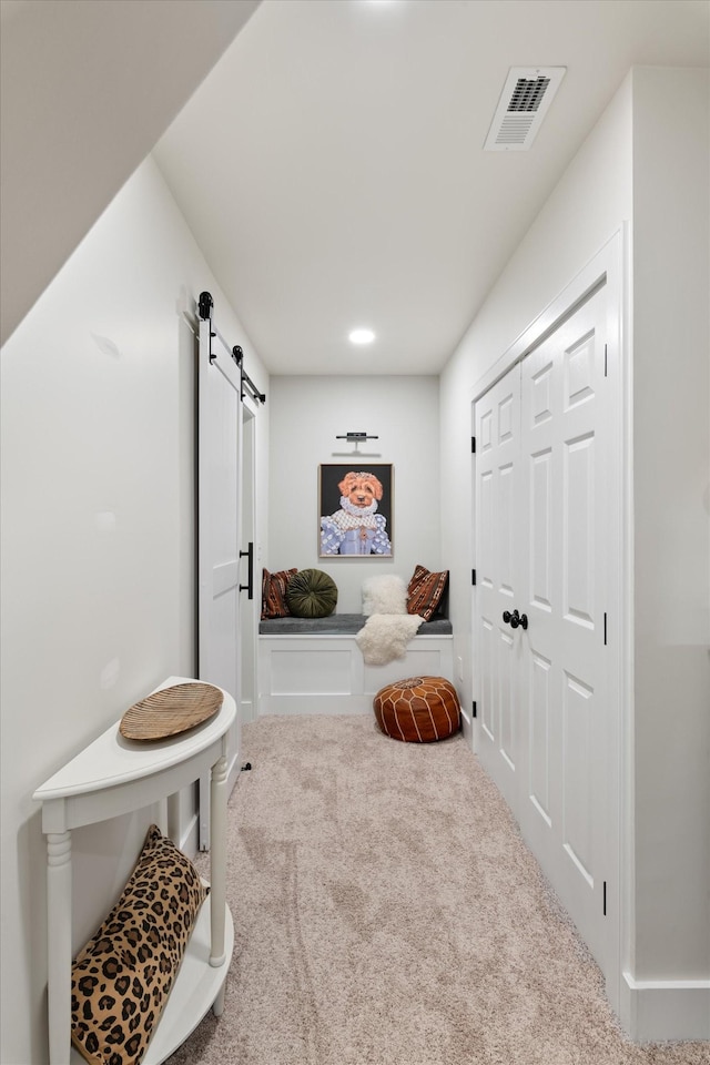 interior space featuring a barn door, carpet flooring, and visible vents