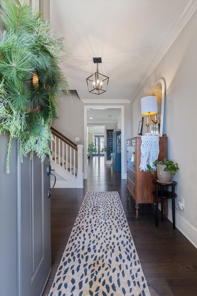 foyer entrance with crown molding, wood finished floors, baseboards, stairway, and an inviting chandelier