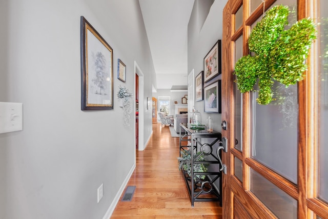 corridor with visible vents, light wood-style flooring, and baseboards