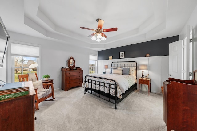 bedroom with carpet floors, ceiling fan, a tray ceiling, and baseboards