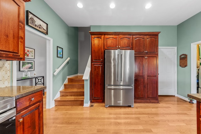 kitchen with recessed lighting, high end refrigerator, baseboards, range, and light wood finished floors