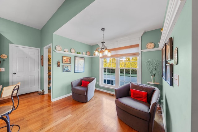 living area with baseboards, a notable chandelier, visible vents, and light wood finished floors