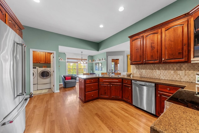 kitchen with tasteful backsplash, light wood-style flooring, appliances with stainless steel finishes, independent washer and dryer, and a peninsula