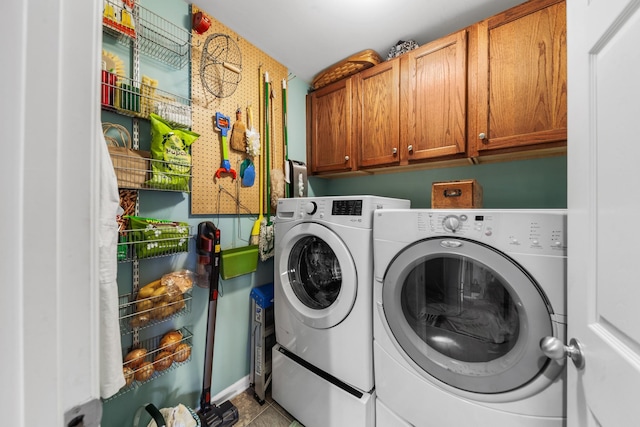 clothes washing area with tile patterned flooring, washing machine and clothes dryer, and cabinet space