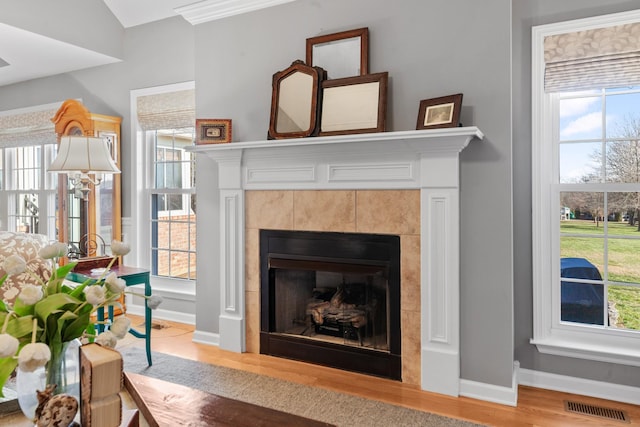 interior space with a fireplace, wood finished floors, visible vents, and baseboards