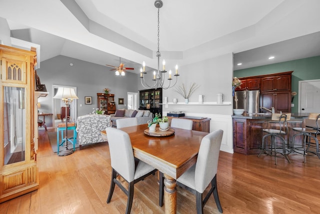 dining space featuring ceiling fan with notable chandelier, light wood-type flooring, and lofted ceiling