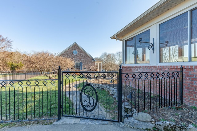 view of gate with a fenced front yard and a lawn