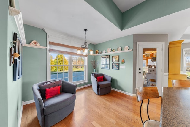 living area featuring baseboards, light wood finished floors, and an inviting chandelier