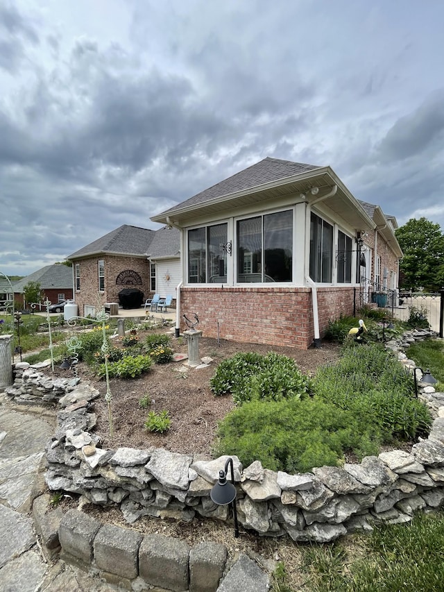 view of property exterior featuring a patio, brick siding, and fence