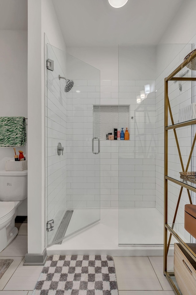 full bath with a stall shower, toilet, and tile patterned floors