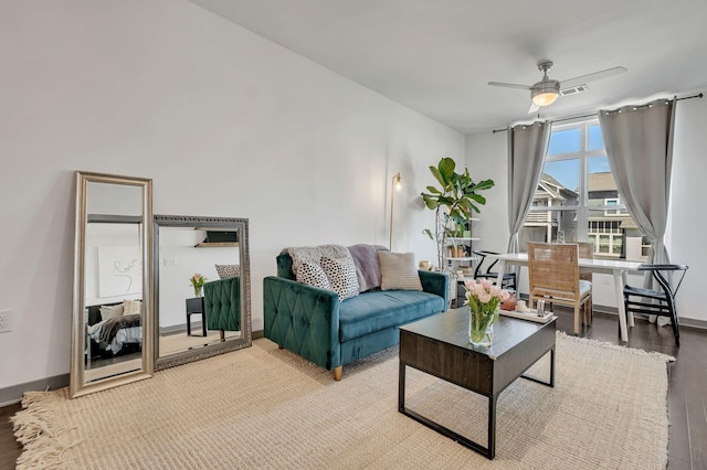 living room featuring a ceiling fan, visible vents, light wood-style floors, and baseboards