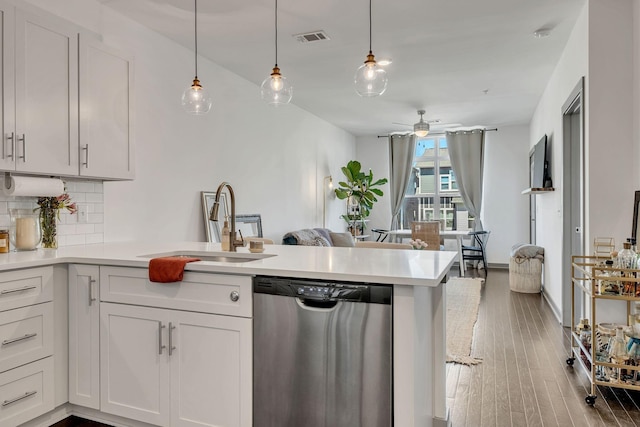 kitchen with visible vents, decorative backsplash, stainless steel dishwasher, a sink, and a peninsula