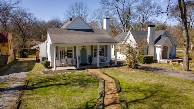 view of front of property with driveway, a chimney, a front lawn, and a porch