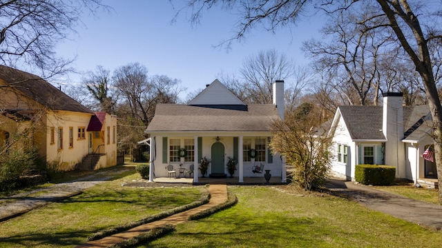 view of front of property featuring aphalt driveway, covered porch, a shingled roof, a chimney, and a front yard