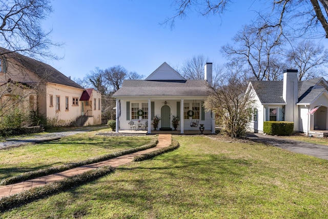 view of front of property with a front yard, covered porch, and a chimney