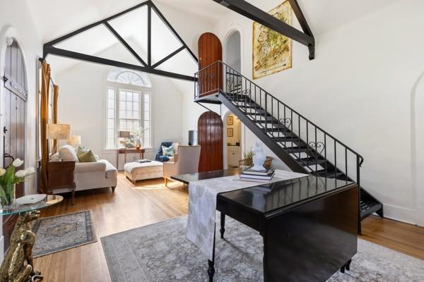 interior space with stairs, arched walkways, high vaulted ceiling, and wood finished floors